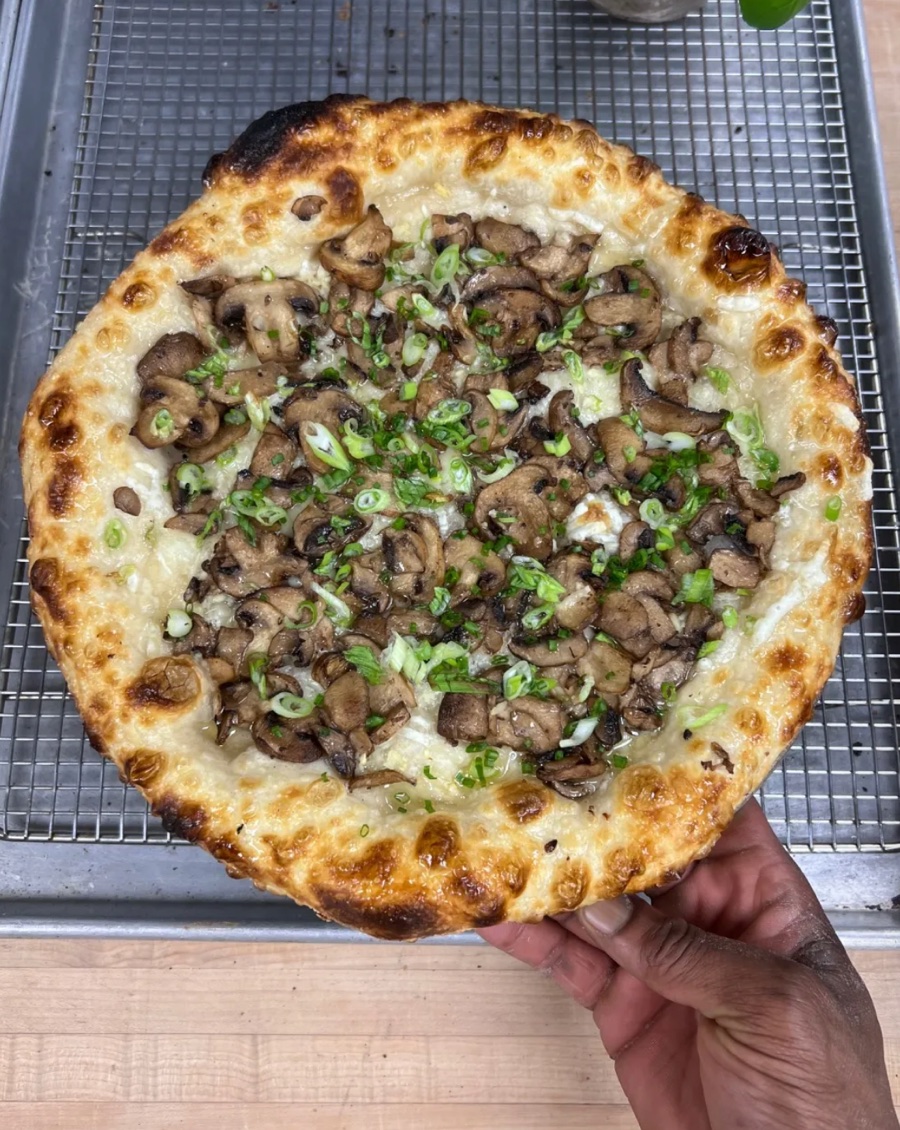 A mushroom and scallion white pizza with a leoparded crust